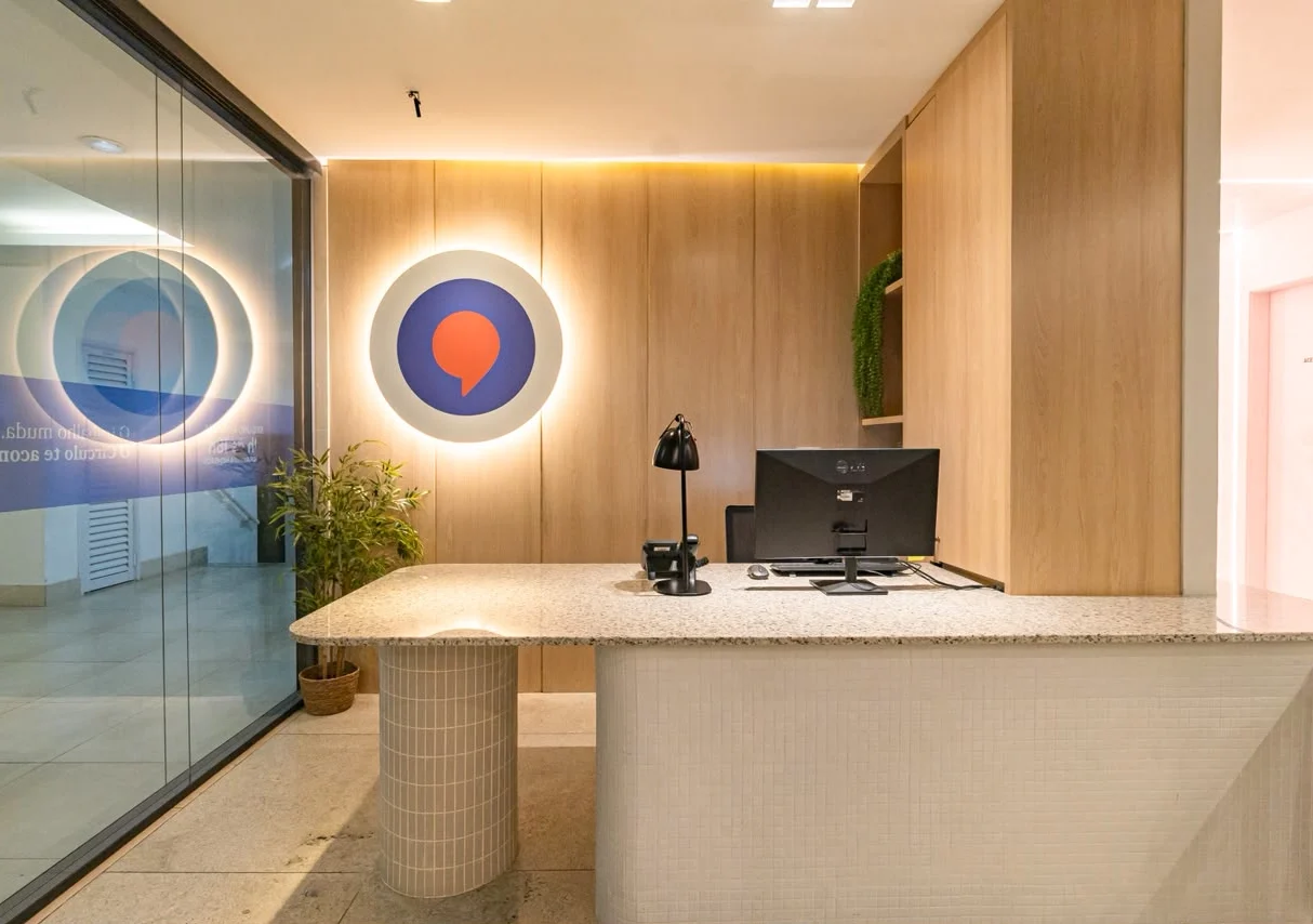 Recepção do Círculo Coworking em Niterói com o balcão de atendimento e o símbolo da marca na parede